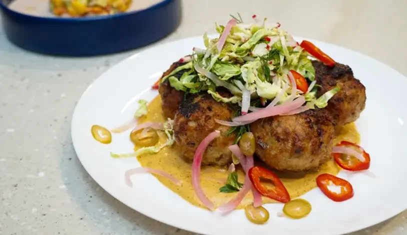 Grilled chicken meatballs with yellow curry sauce and cabbage slaw