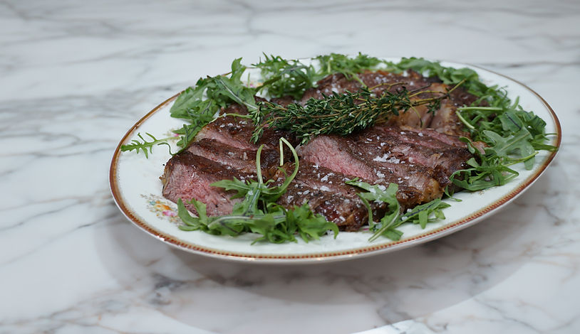 Sliced ribeye steak with arugula and fresh herbs